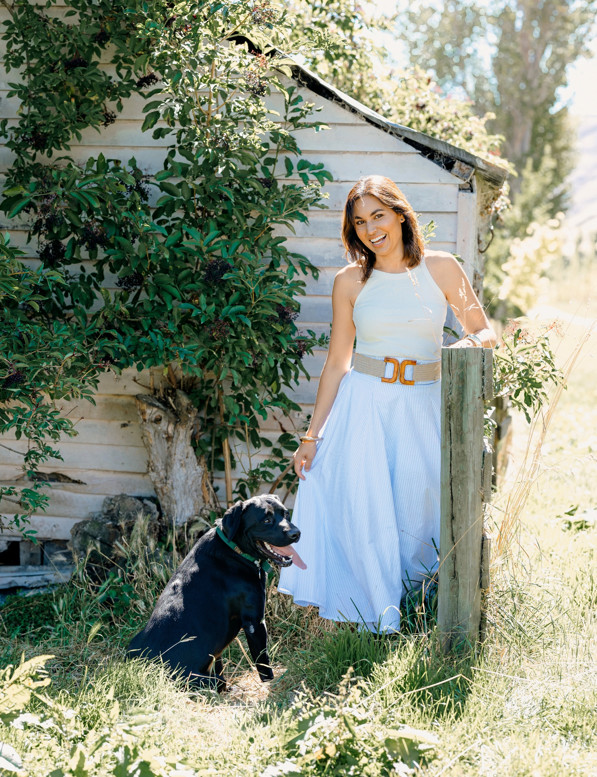 Nadia Lim leaning on fence beside her black dog