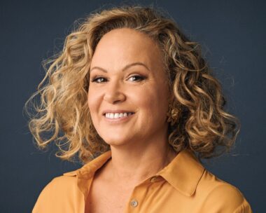 Leah Purcell in a yellow top in front of a black background
