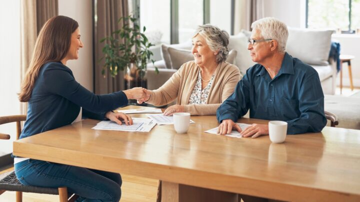 An elderly couple sitting at a table to discuss their retirement planning with an expert