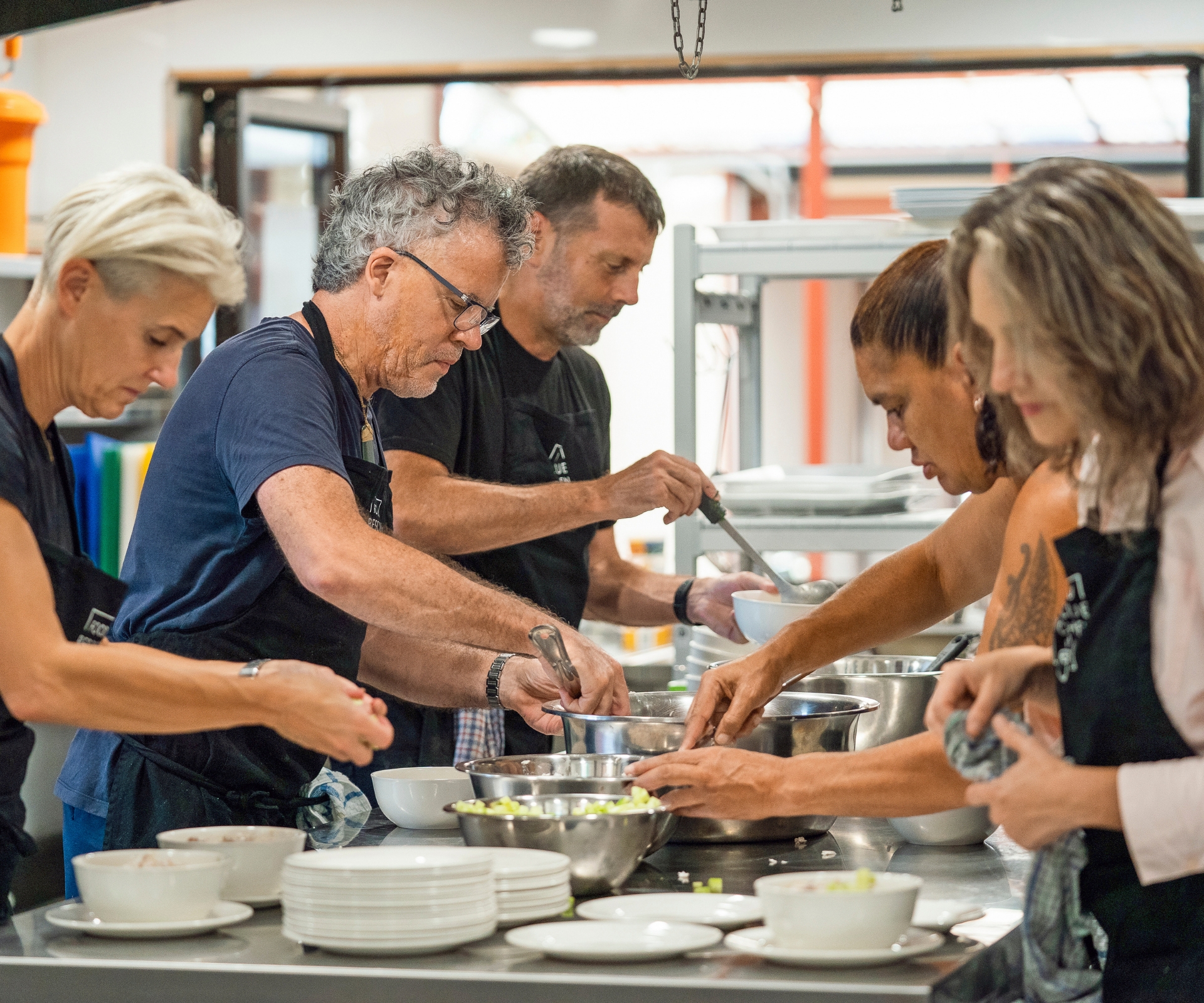 Peter Gordon in the kitchen with other chefs cooking with food scraps