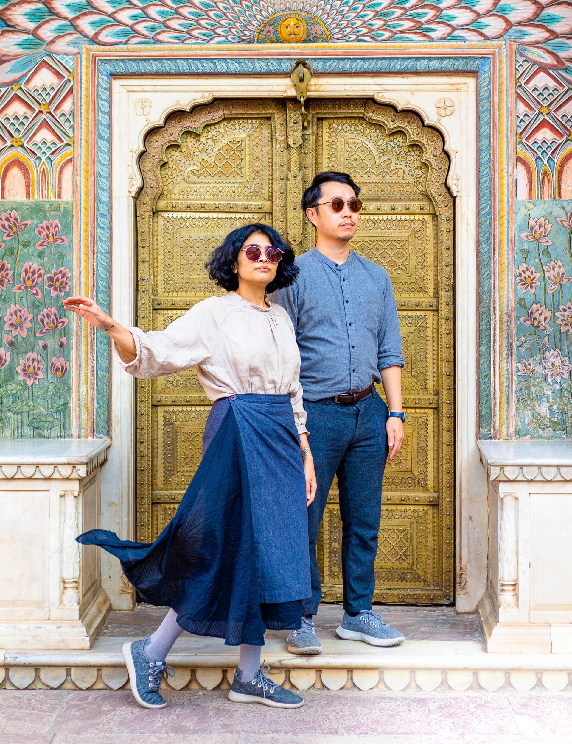 Ankita and Calvin in front of a brightly coloured mural around a golden doorway