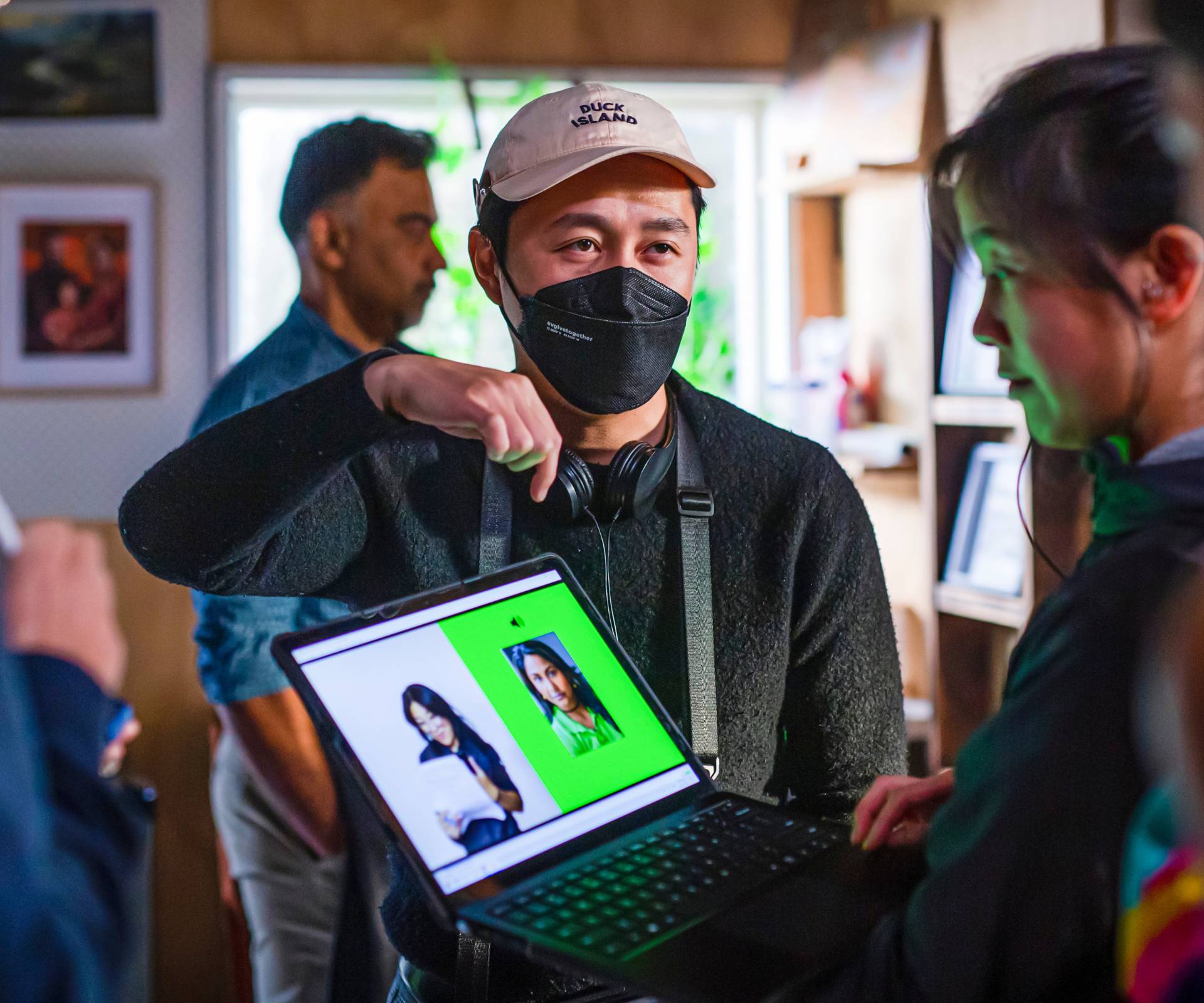 Calvin behind the scenes of filming. pointing to something on a screen and explaining to a colleague