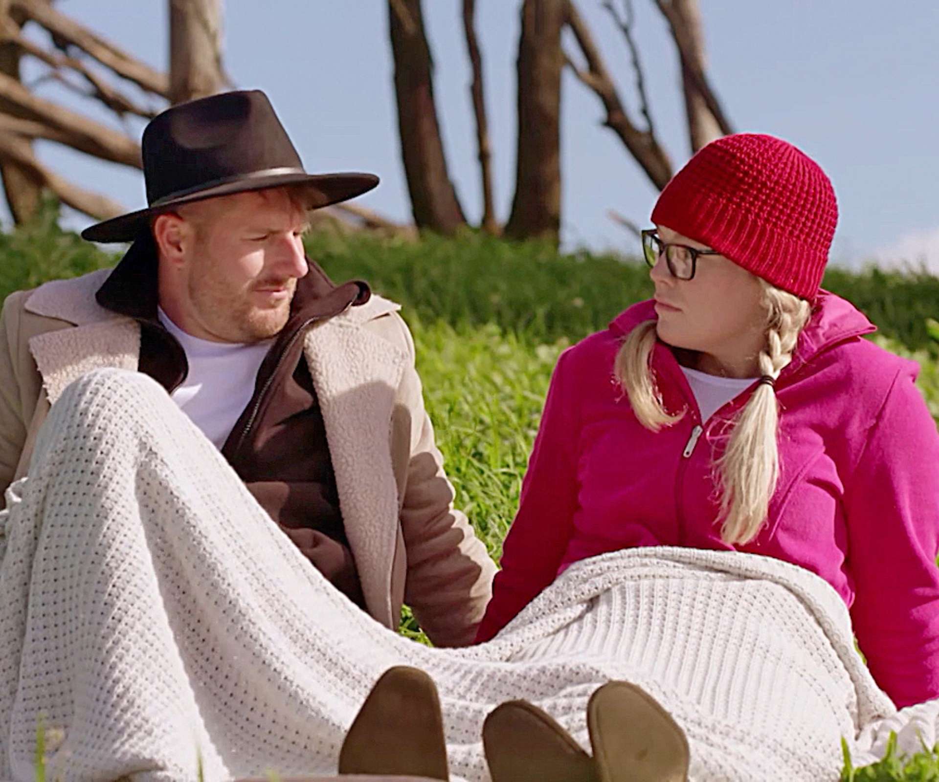 Bryce and Melissa on their MAFS honeymoon sitting under a blanket with beanies on