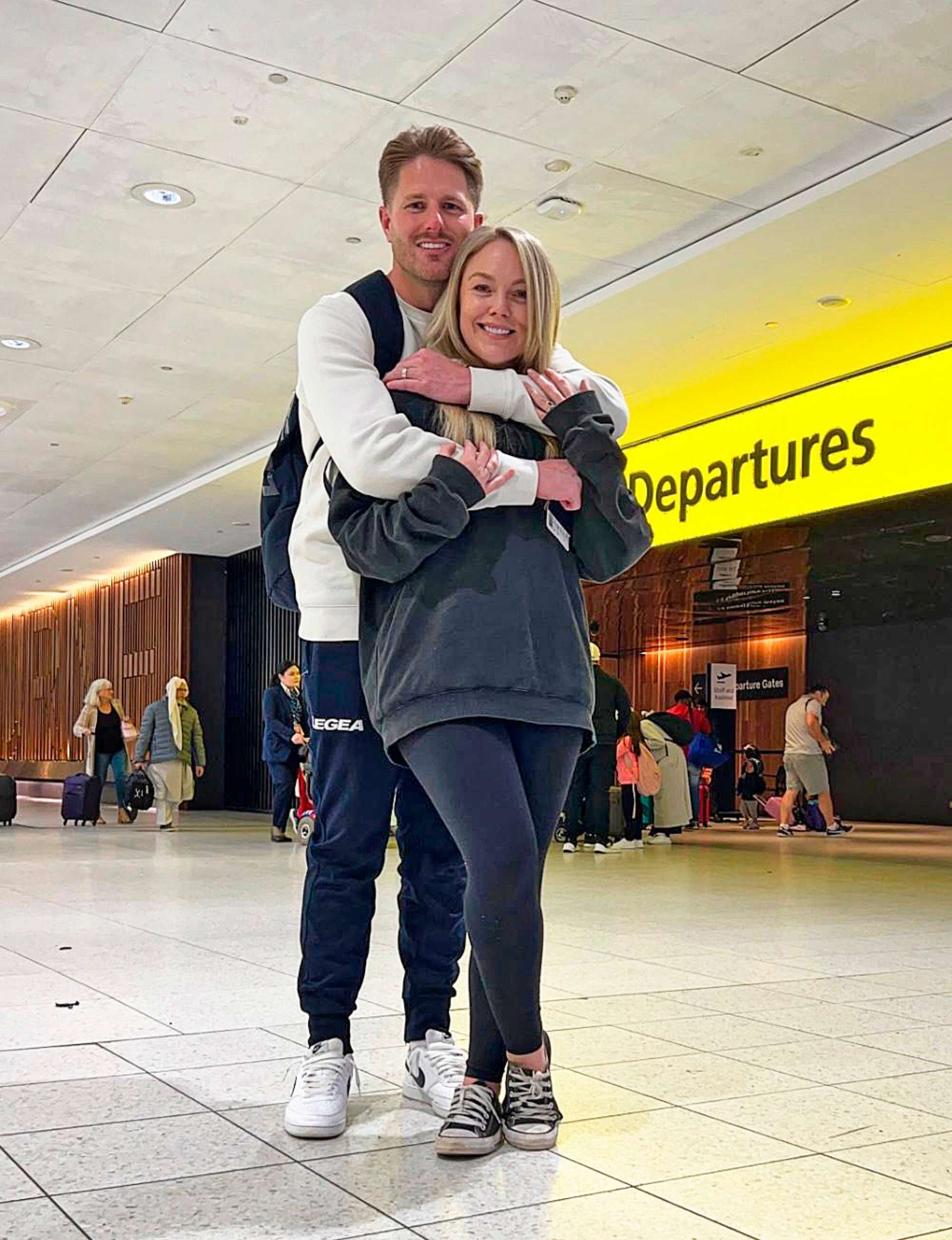 Melissa and Bryce in front of the Departures sign at the airport