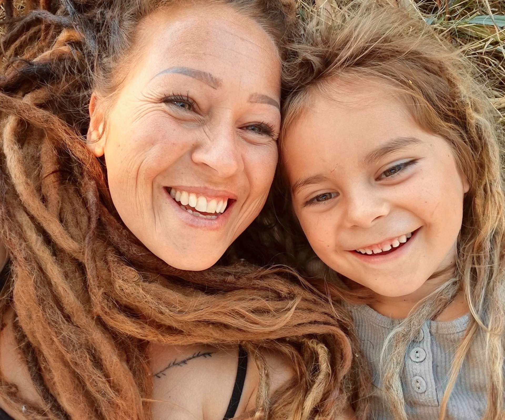 Jasmine&rsquo;s mother Keri and younger brother both laying on the grass with their dreadlocks surrounding their faces