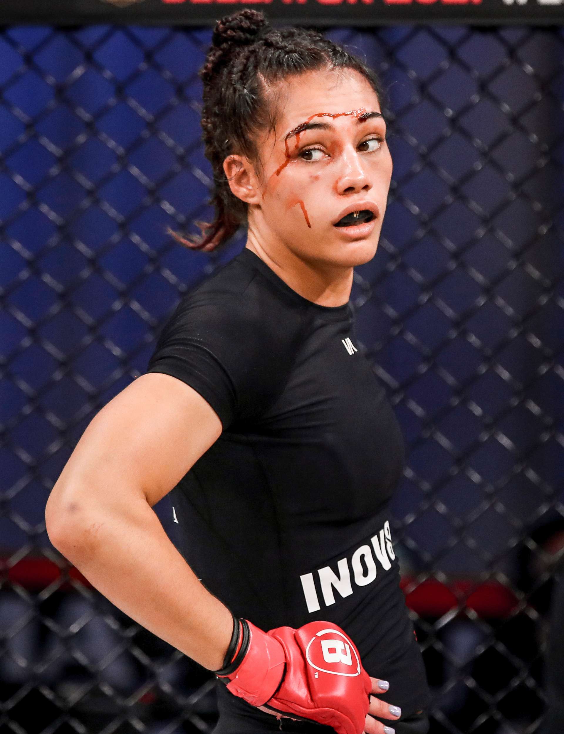 Janay Harding with blood on her face, wearing a mouthguard and MMA gloves
