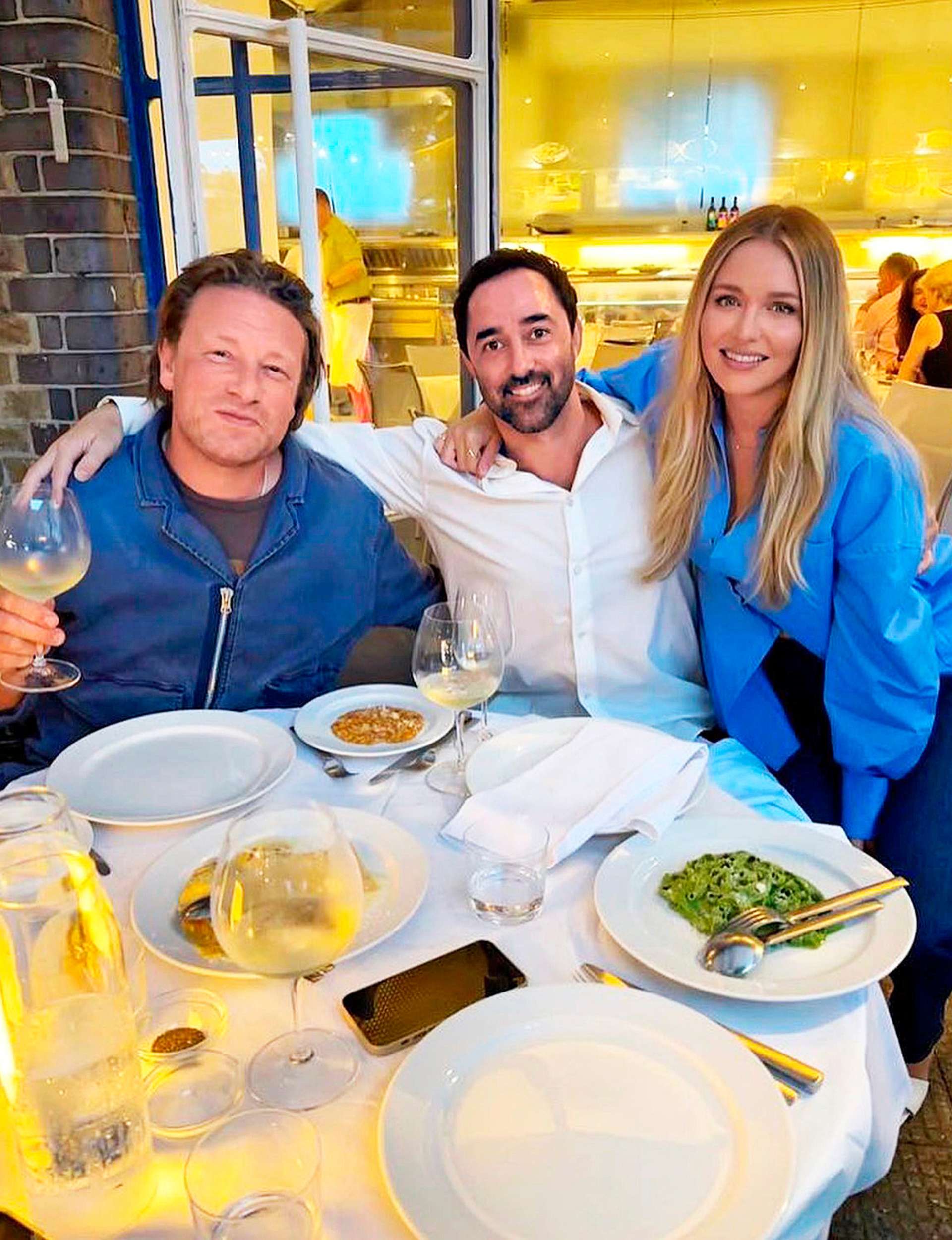 Andy, Jamie and Andy's wife sitting around a round table with wine and food