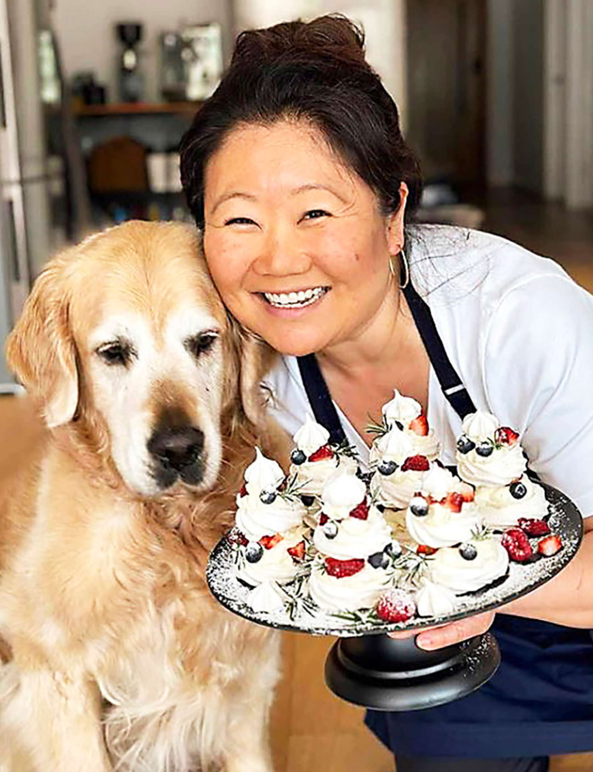 Nagi Maehashi holding a plate of food beside golden retriever Dozer