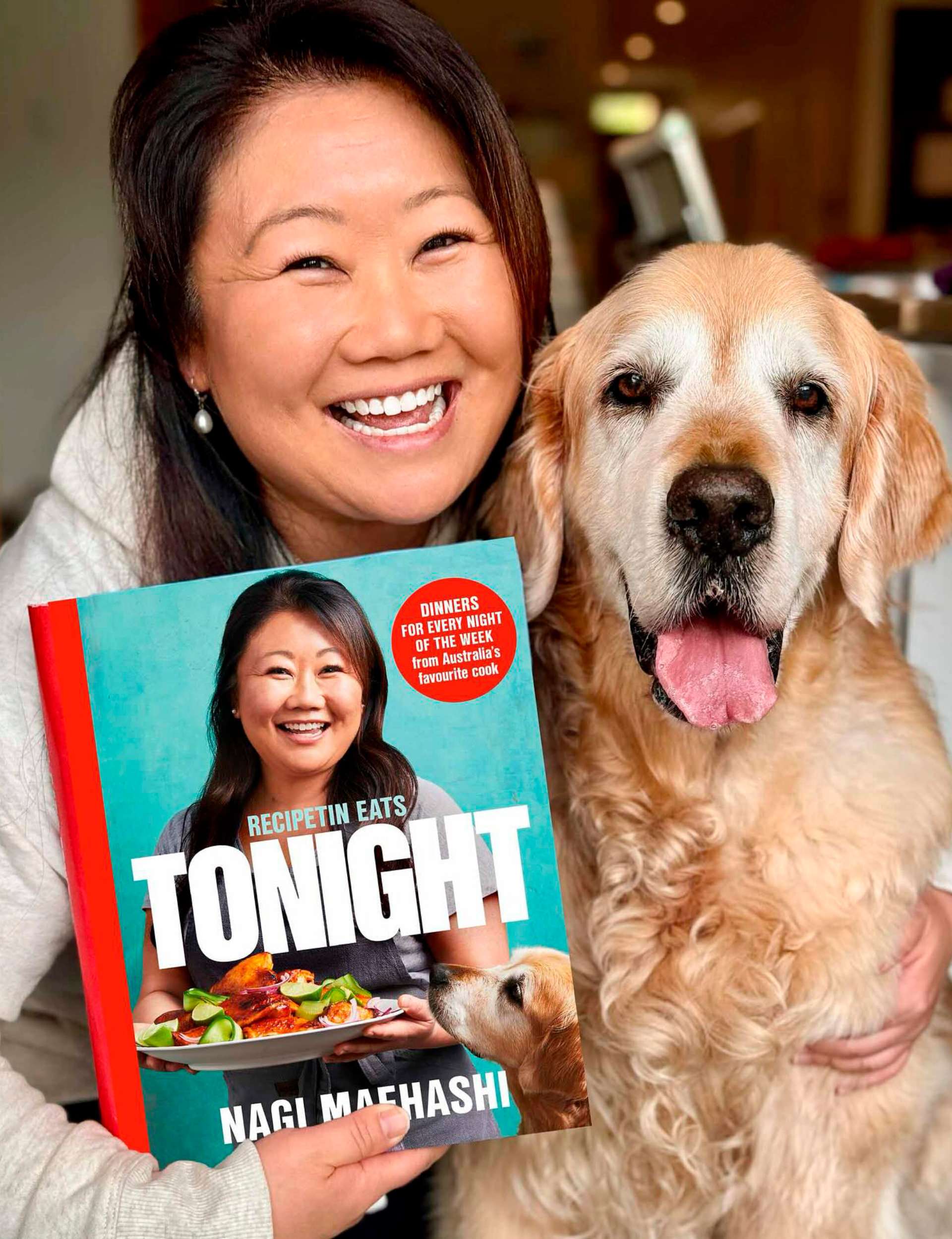 Nagi Maehashi holding up her cookbook beside dog Dozer