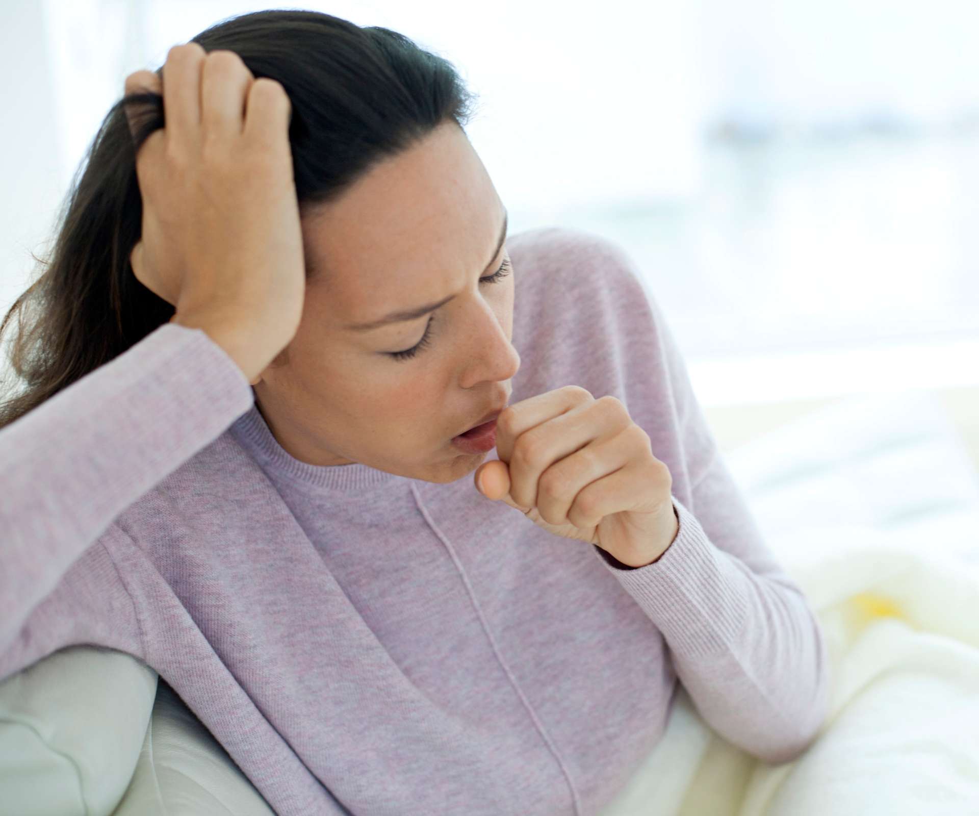 Woman coughing in to her fist