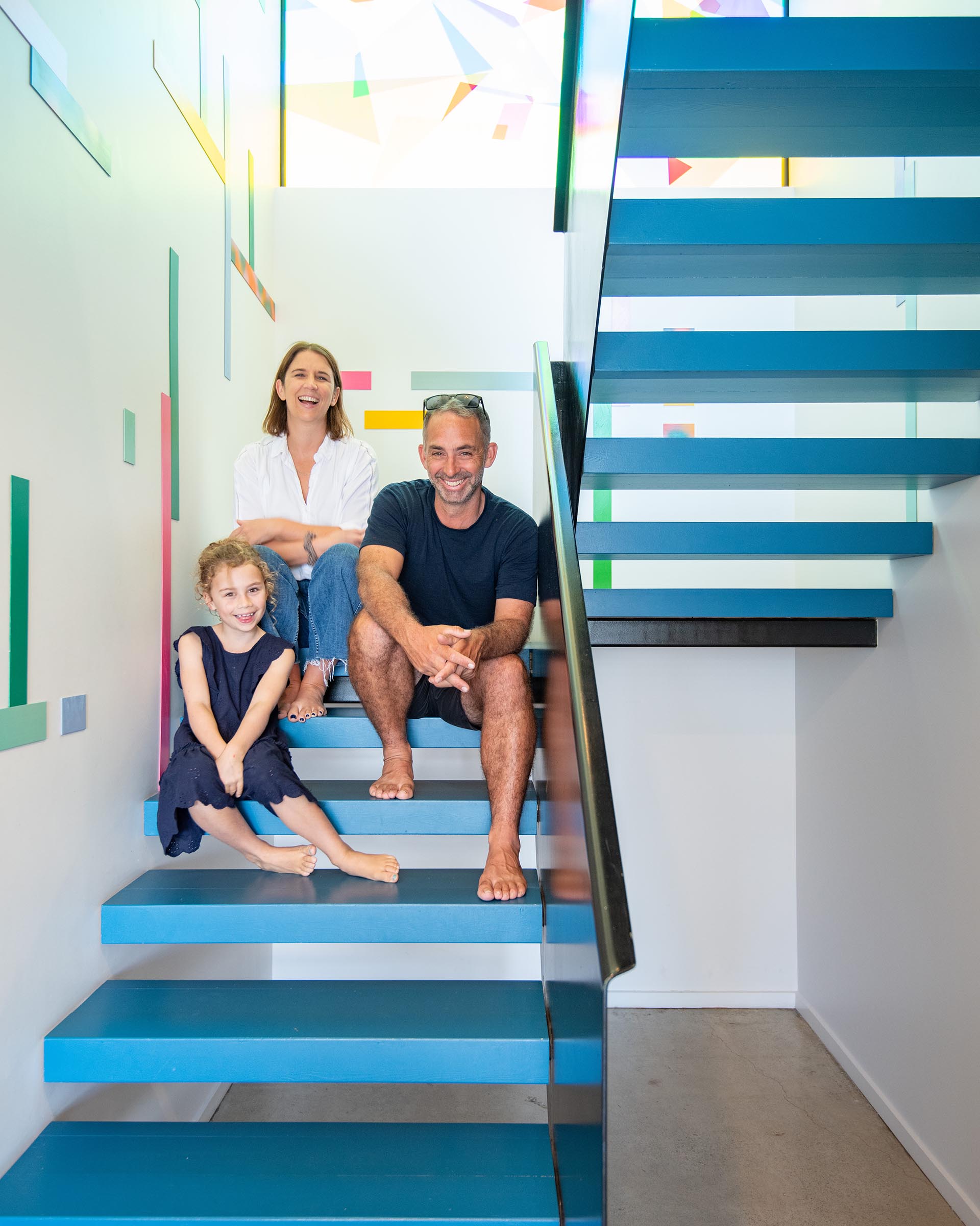 Family sitting on the floating staircase painted in Resene Spinnaker and balustrade in Resene Foundry
