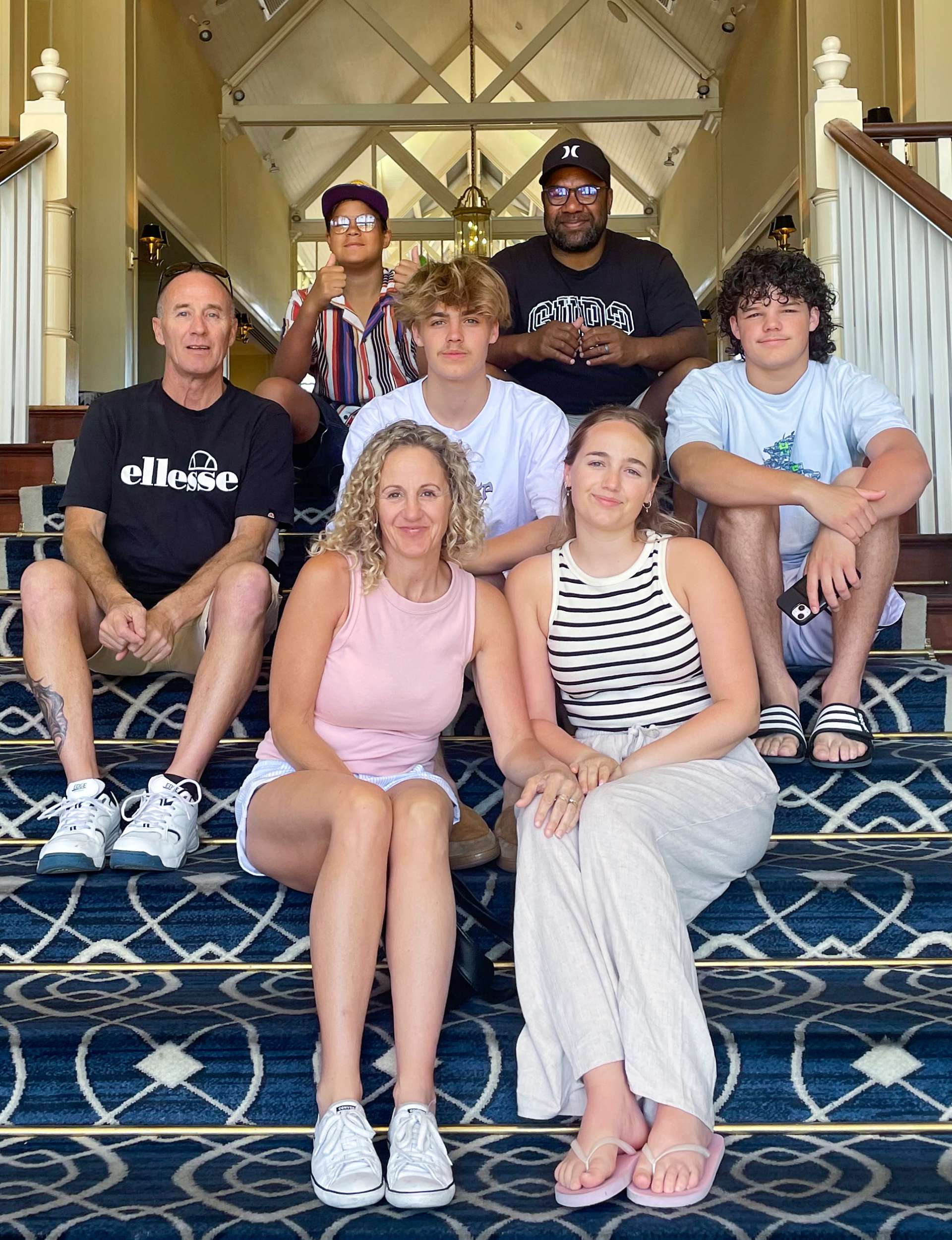 Siale Tunoka with his family sitting on some stairs in Australia