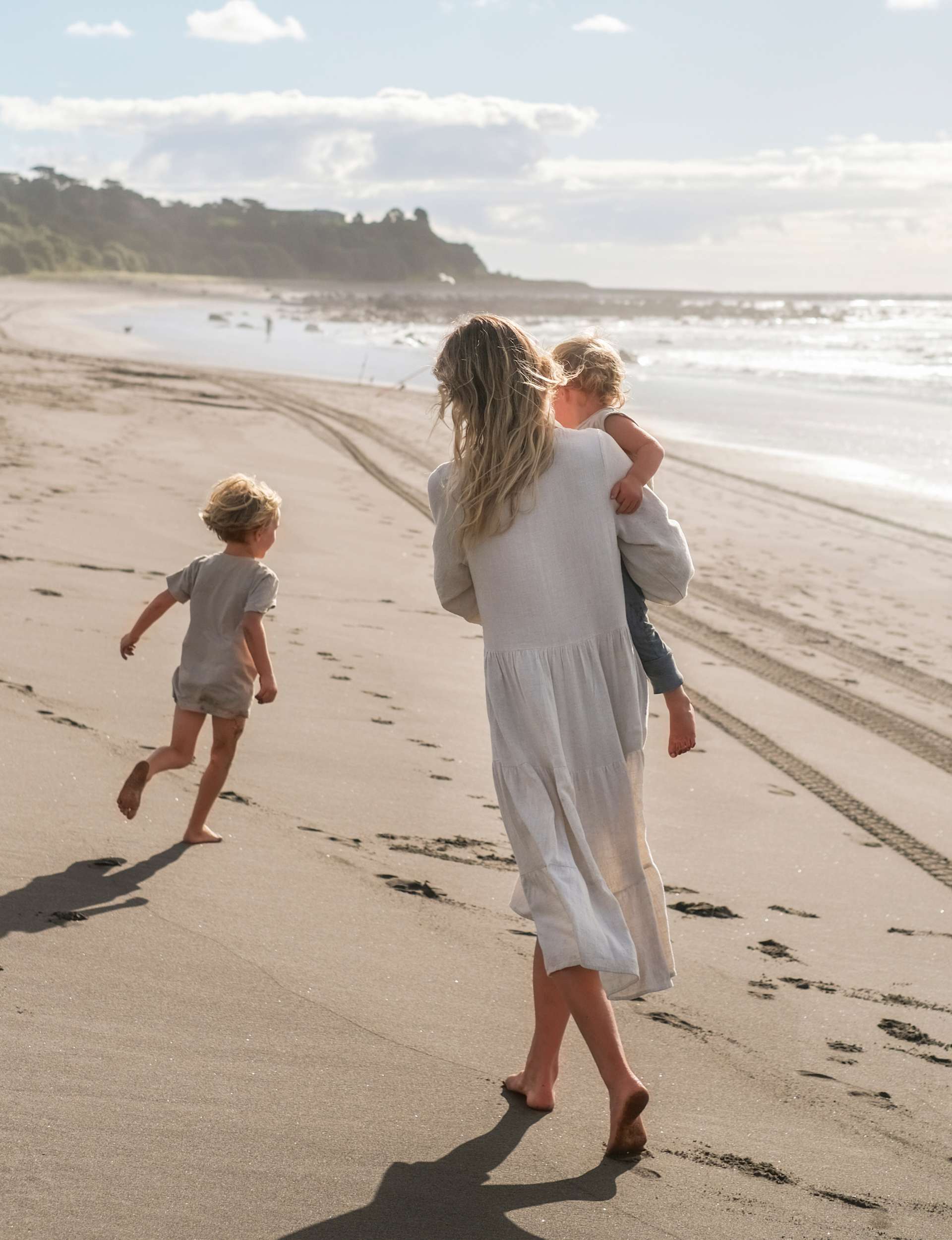 Chelsea Winter walking down a beach with her kids