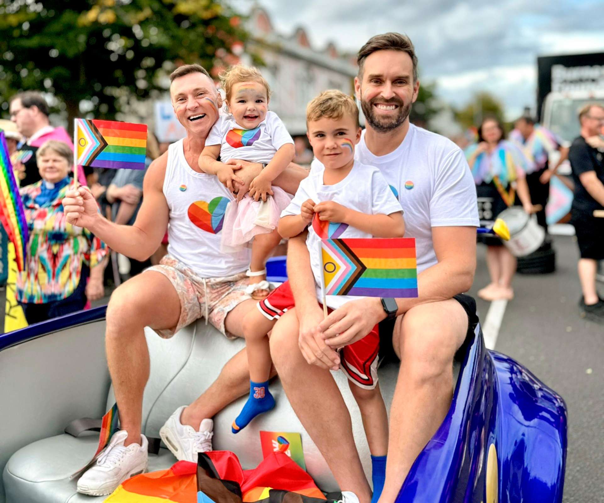Christian and Mark with their kids on the back of a float in a Pride parade