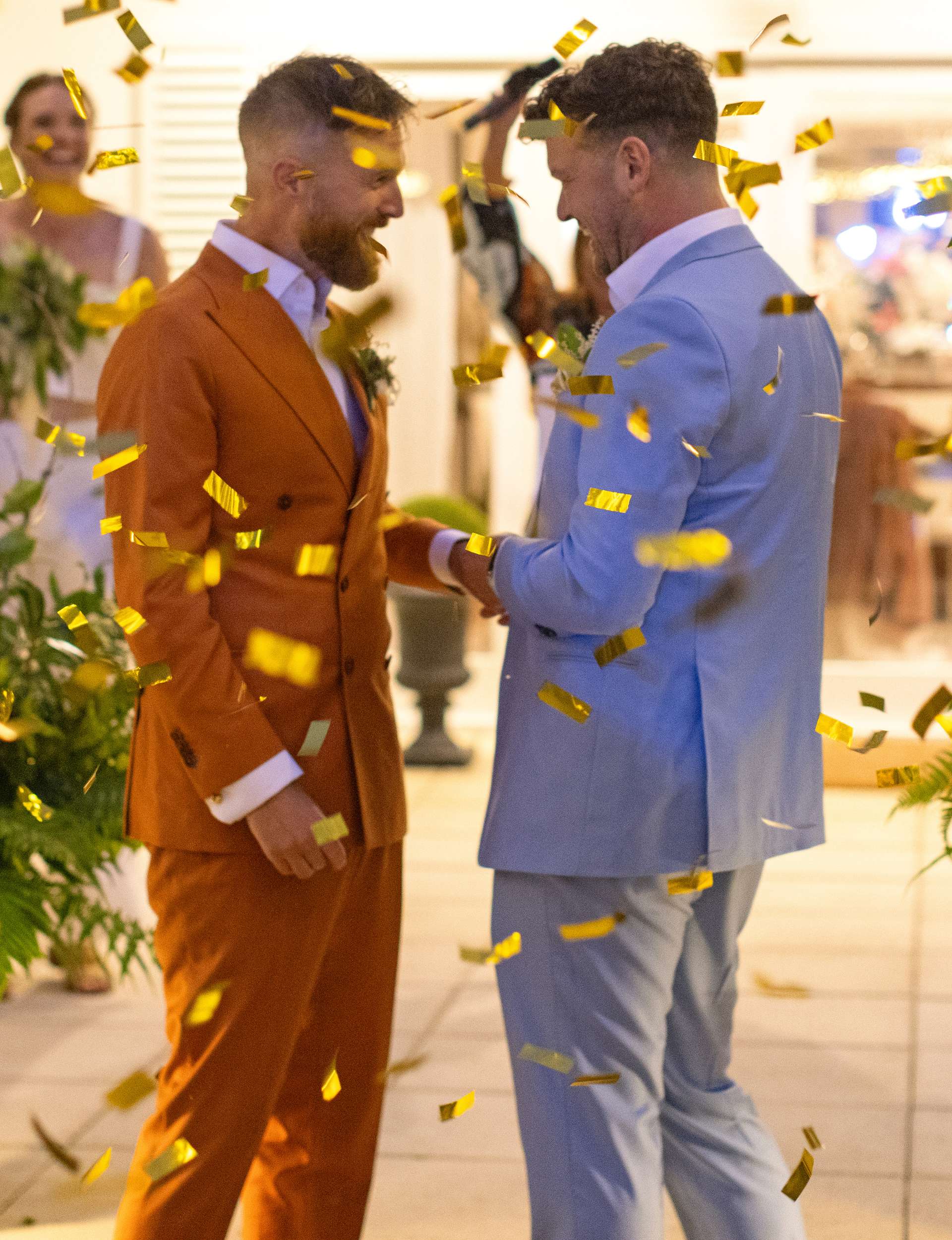 The grooms celebrating in a rain of golden confetti