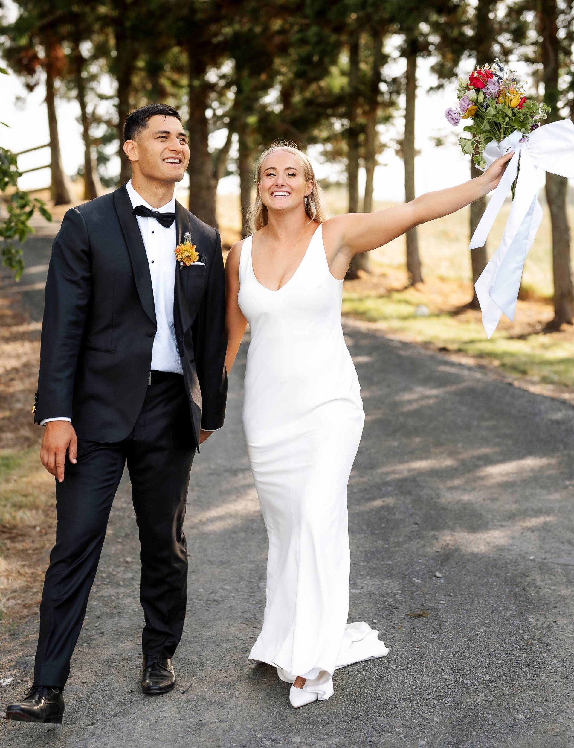Grace and Rameka walking up a road celebrating on their wedding day