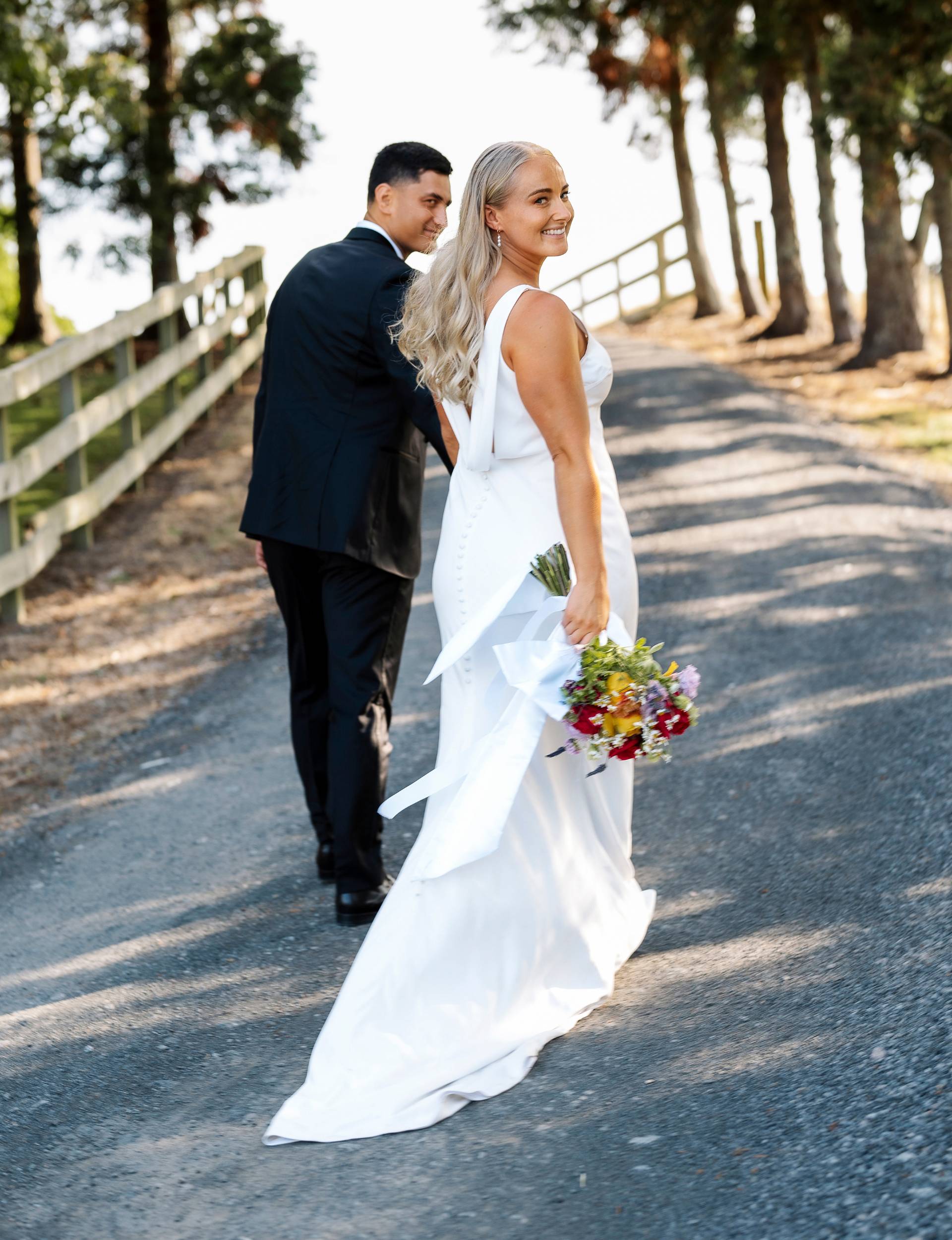 Grace and Rameka walking up a road on their wedding day
