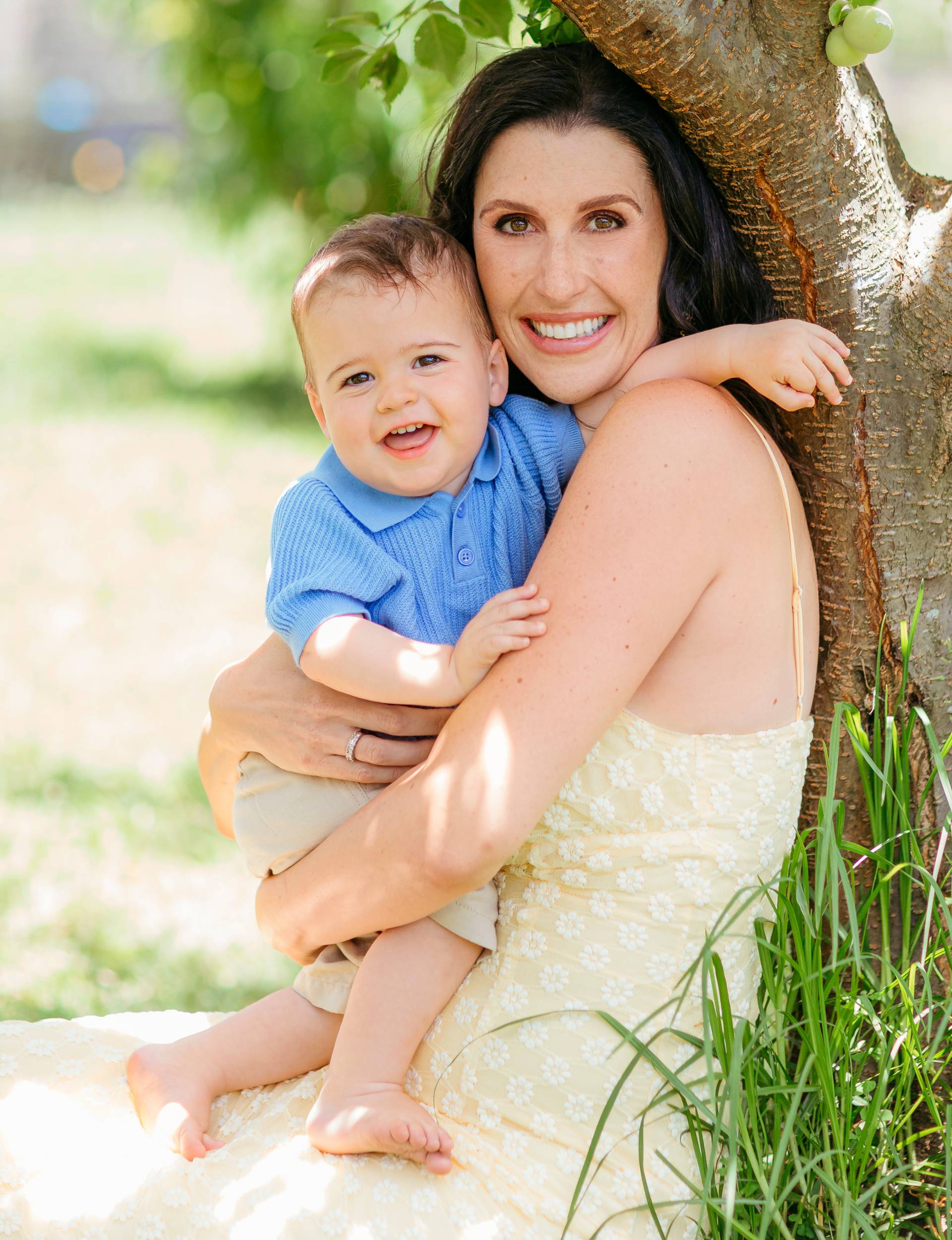 Nadine holding Frankie while sitting against the base of a tree