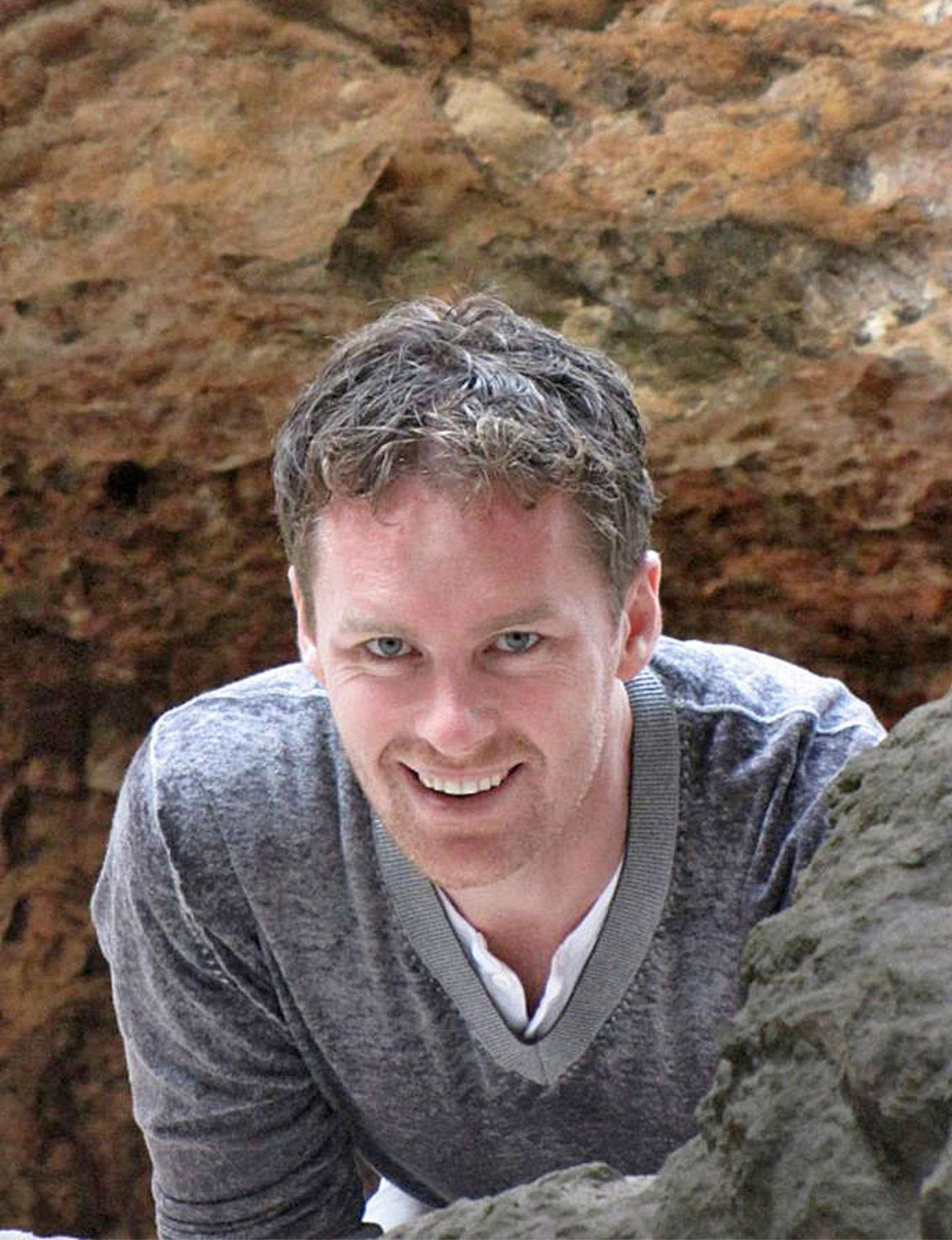 Man smiling wearing grey sweater.