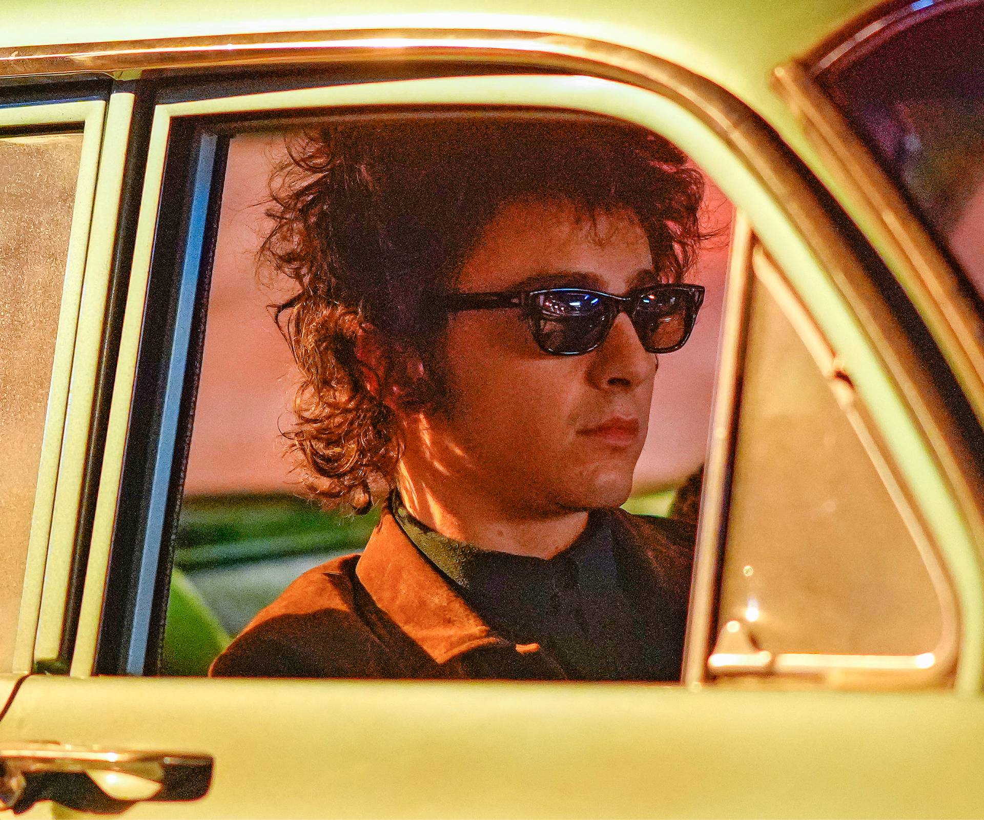 Timothée Chalamet driving a car as Bob Dylan