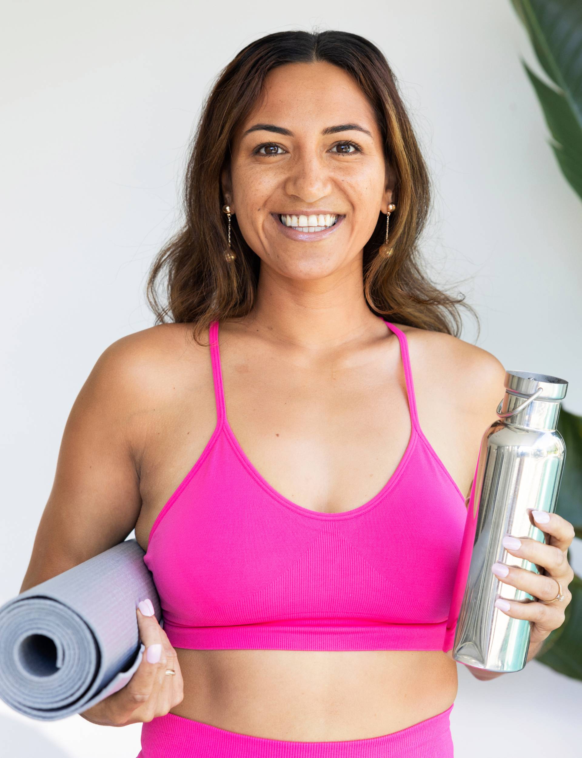 Woman with yoga mat and drink bottle wearing a sports bra