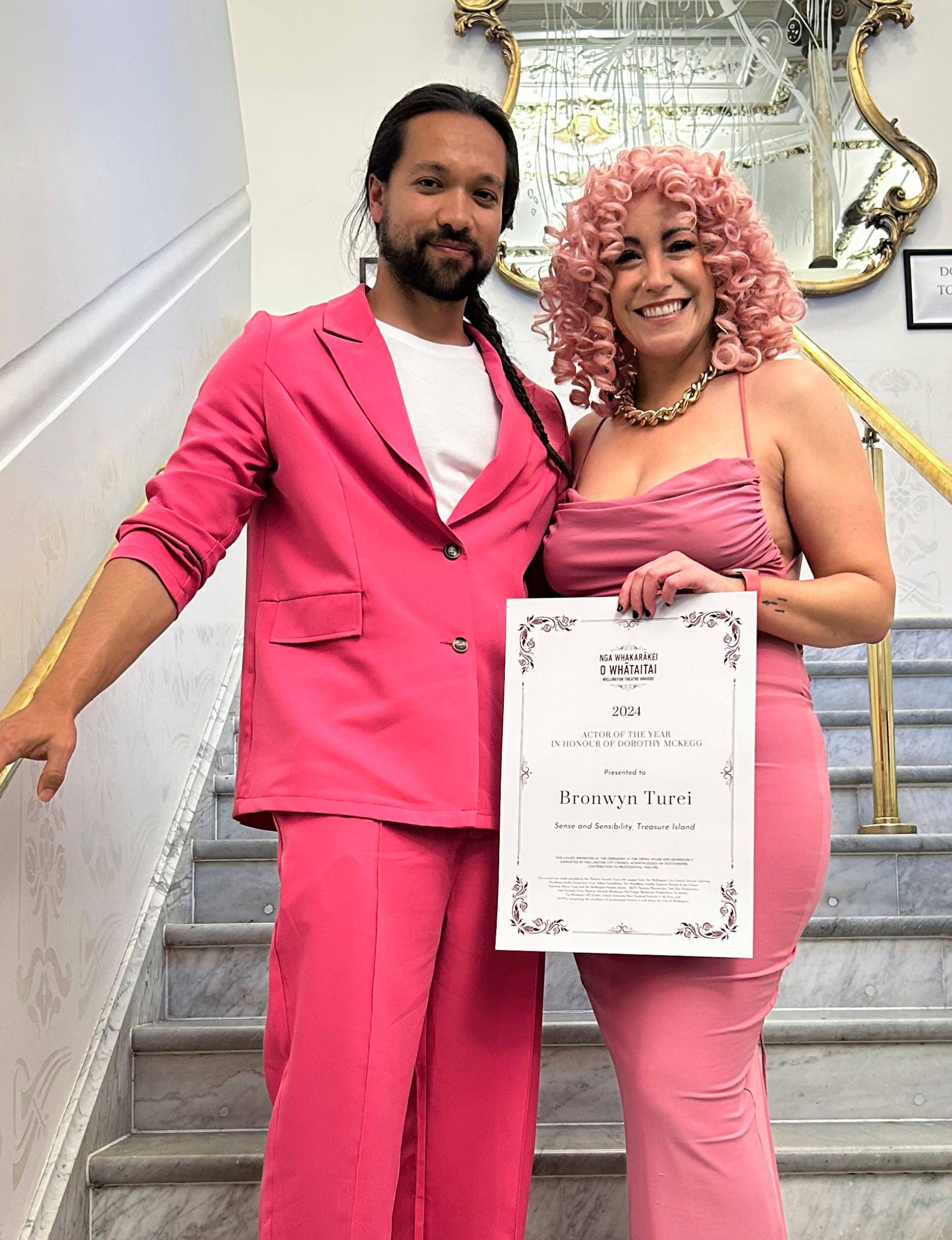 Bronwyn Turei wearing pink with her partner as she accepts an award