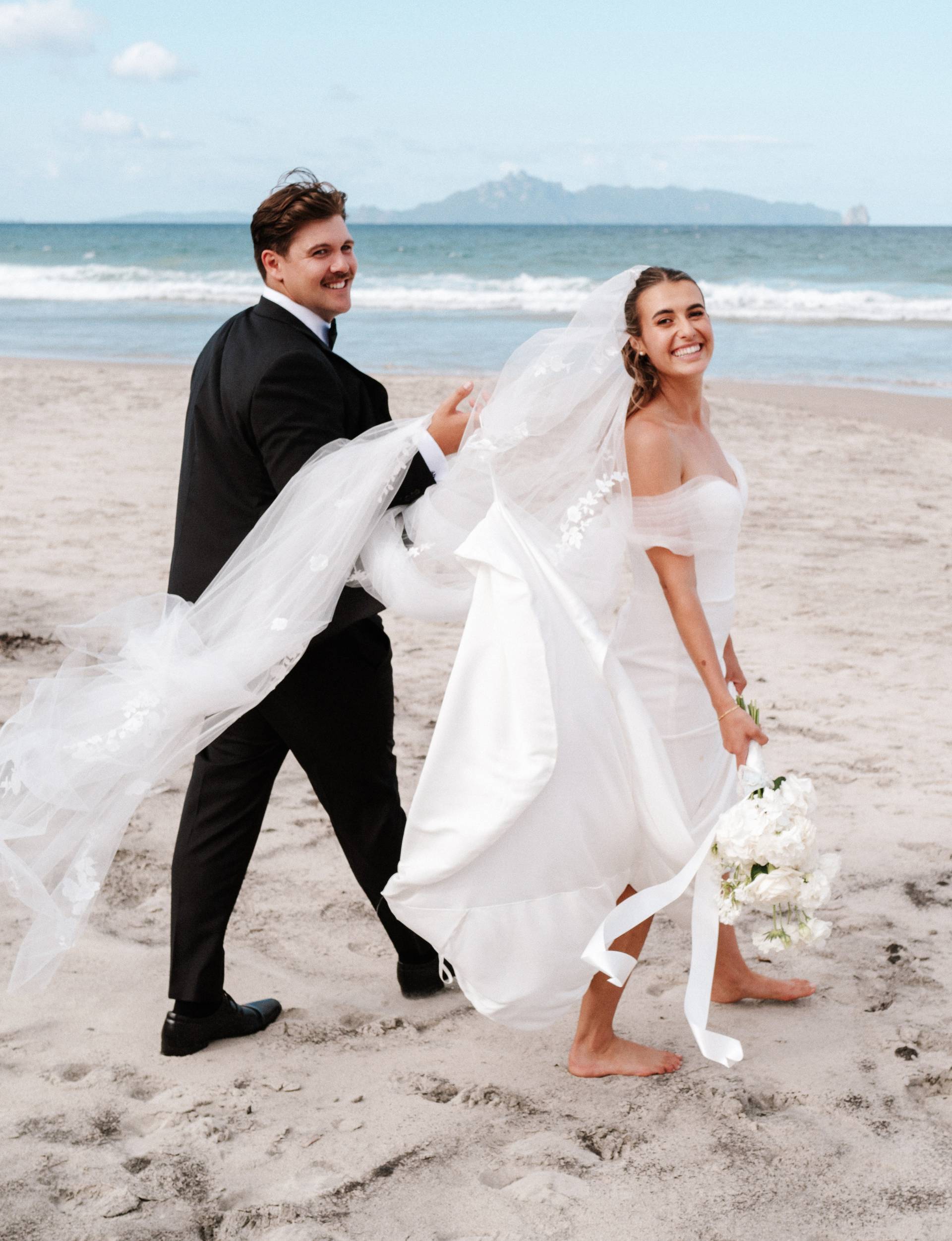 Kelsi and Andrew walking down the beach on their wedding day