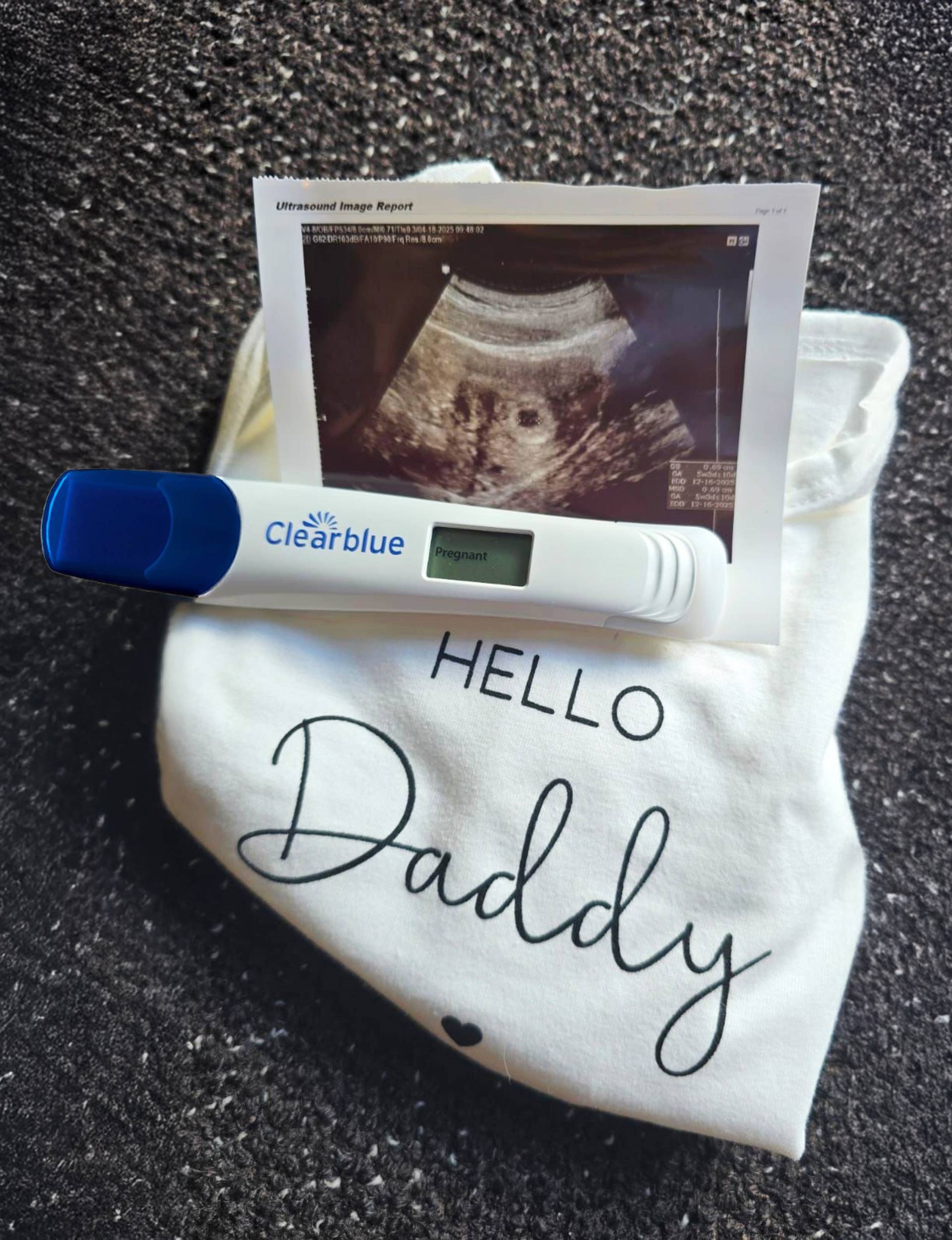 Kim Crossman's pregnant scan and test with a 'Hello Daddy' baby romper