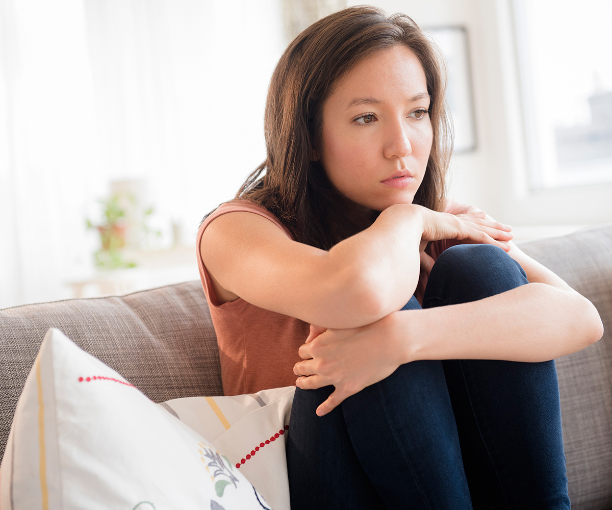 Woman looking sad on couch alone
