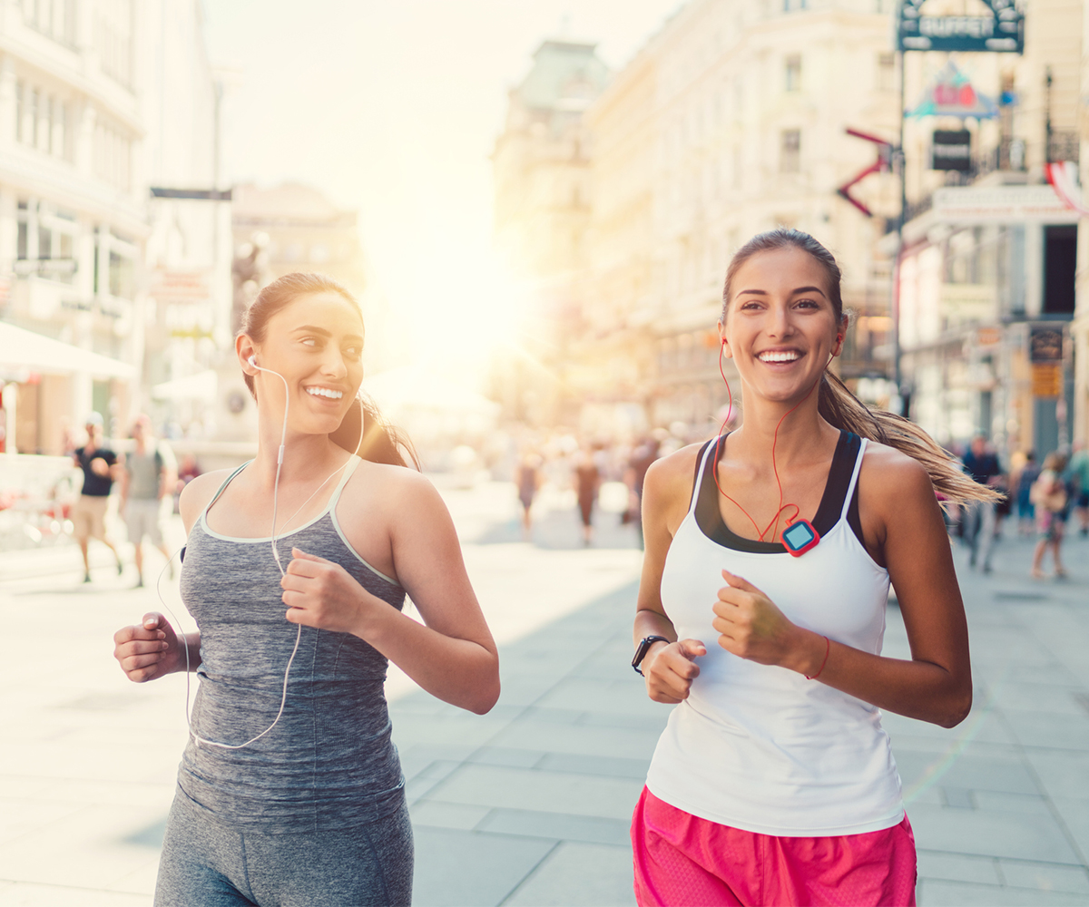 Two women jog through city