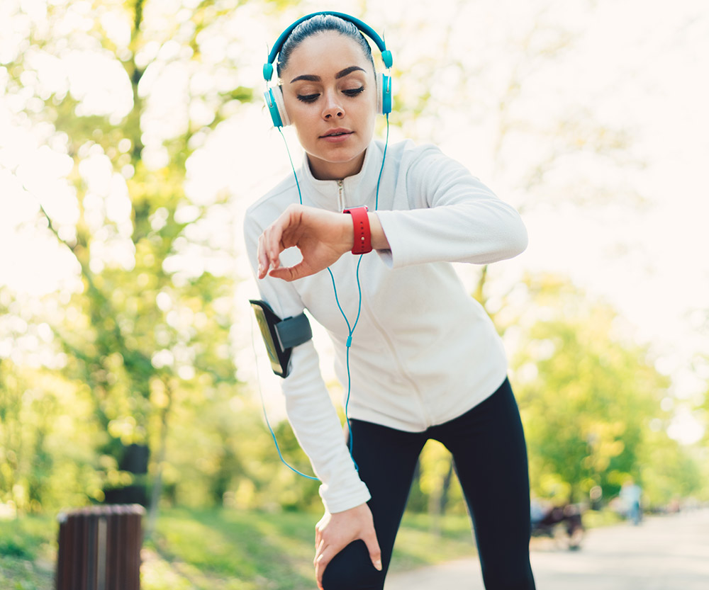 woman running looking at fitness tracker