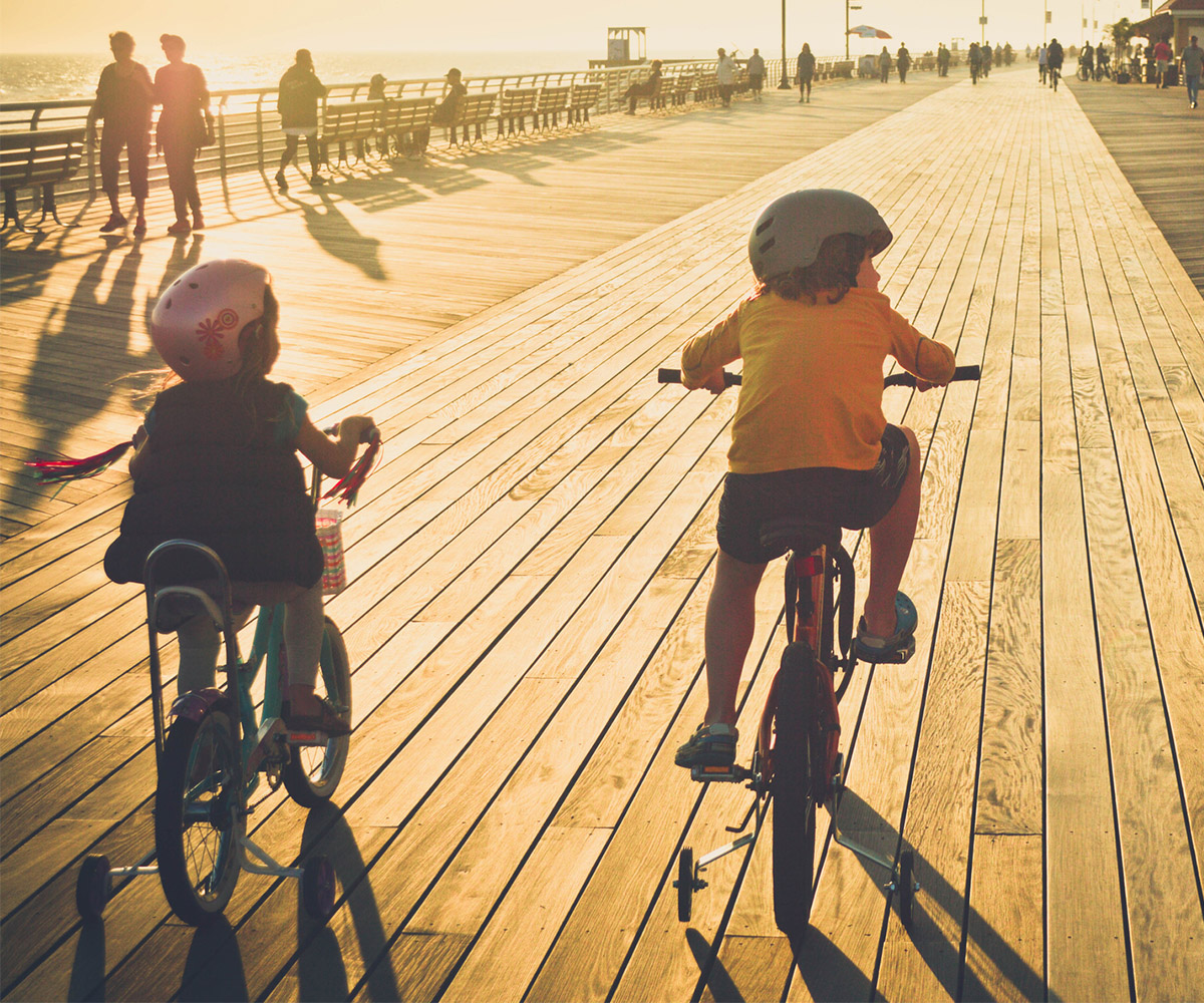 Family riding bikes along beach boardwalk