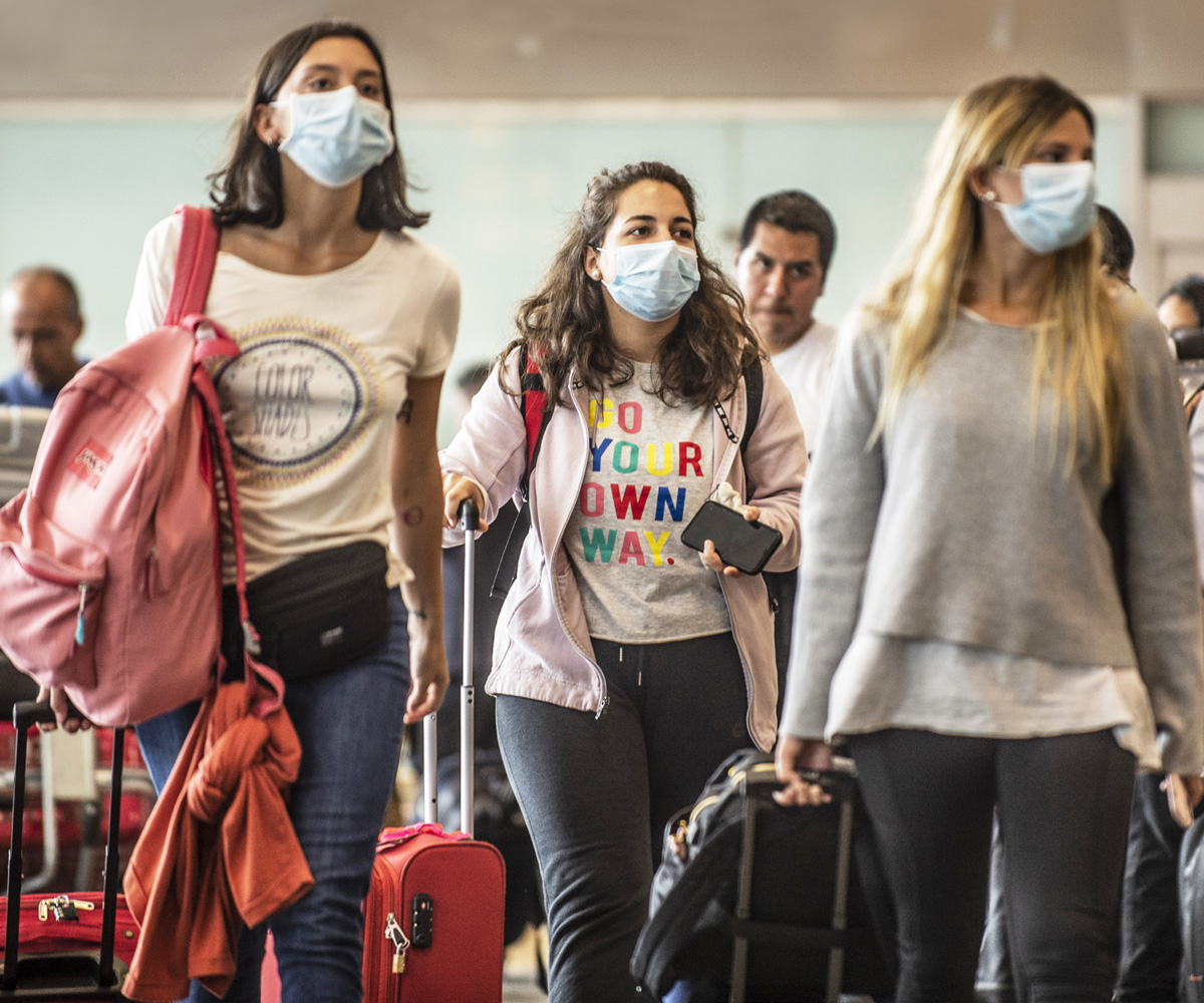 Girls walking through airport wearing face masks