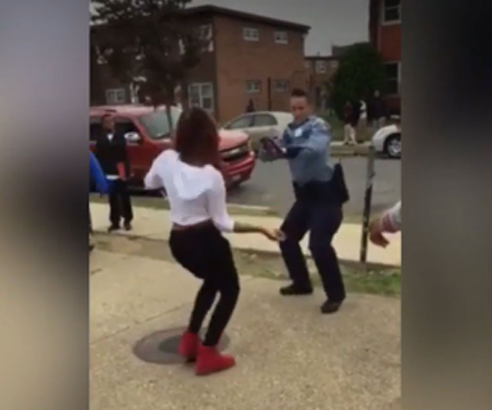 Female police officer in dance-off with teen on sidewalk